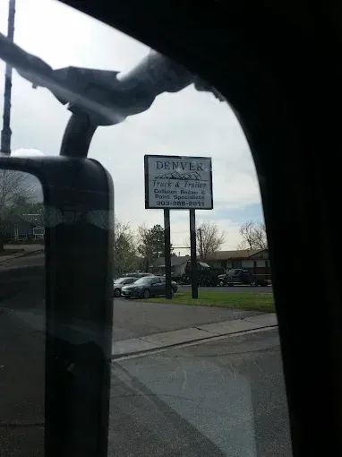 Denver Truck & Trailer roadside sign for collision repair and paint specialists, seen from a truck cab