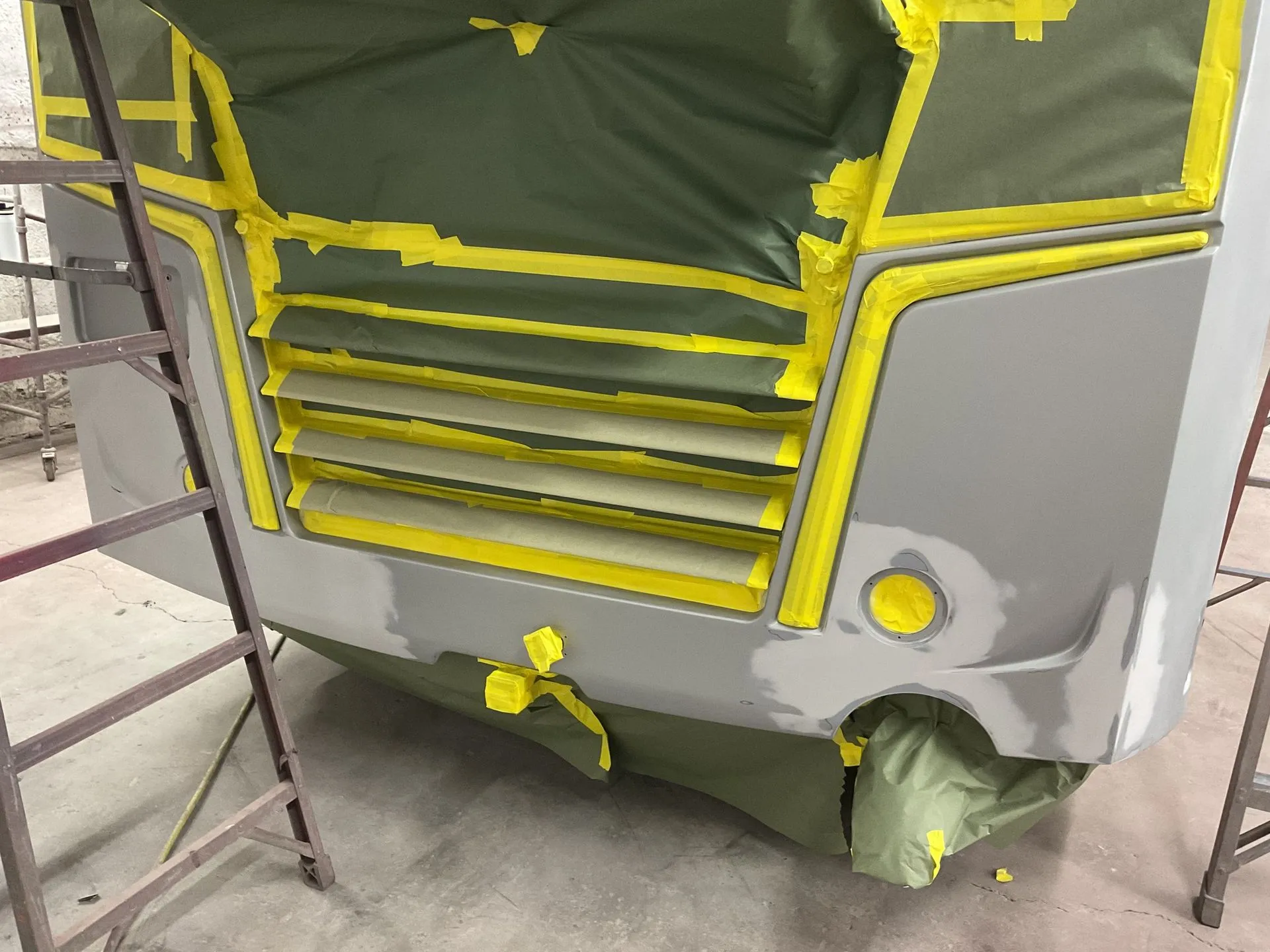 Fiberglass truck front end masked with yellow tape and primed for paint in the shop