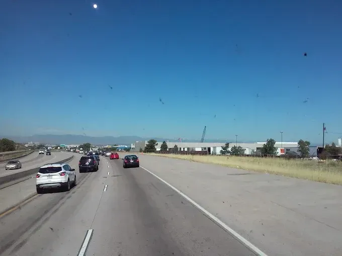 View through a truck windshield of highway traffic with mountains on the horizon