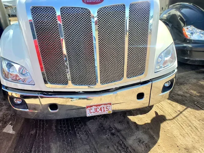Close-up of a white semi truck’s chrome mesh grille and front bumper